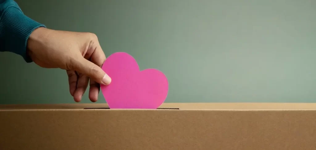 Canadian fundraising donor putting pink paper heart in cardboard donation box