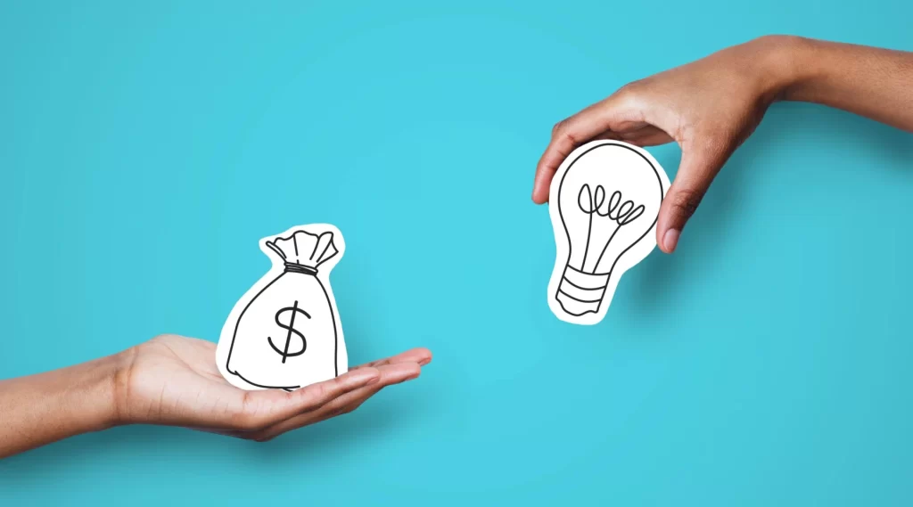 Hand holding money bag and another hand holding a lightbulb against a blue background